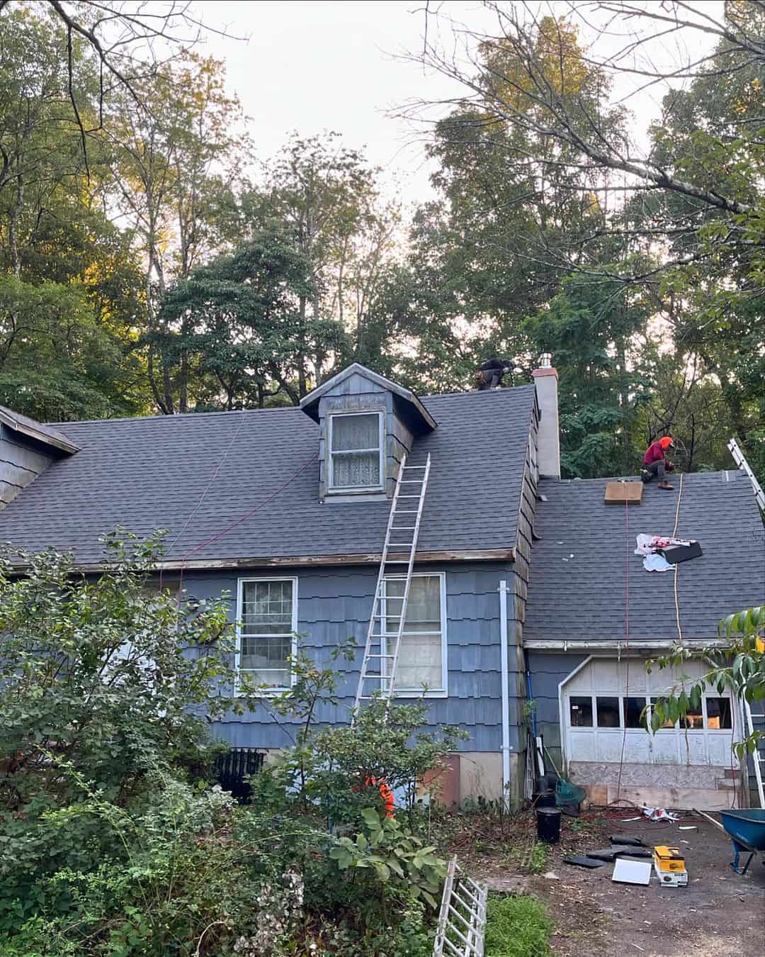 Roofing crew working around a dormer on a shingle roof