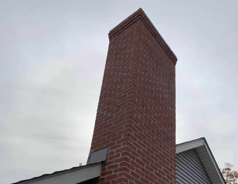 Tall brick chimney above a gray shingle roof