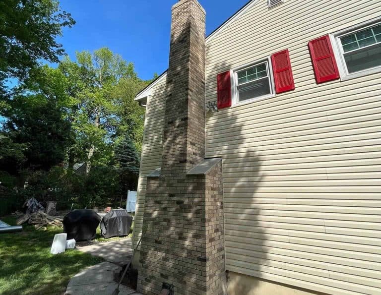 Tall exterior stone chimney on a beige house Tall exterior stone chimney on a beige house